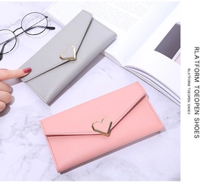 Detail of grey and pink long envelope wallets with golden heart clasps on marble background