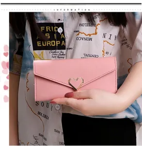 Close-up of pink long envelope wallet featuring a decorative gold hollow heart buckle