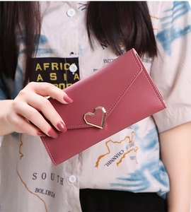 Macro view of burgundy long envelope wallet with gold heart clasp and stitching