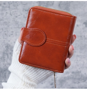 Detail of brown oil wax leather wallet with metallic zipper and buckle strap design