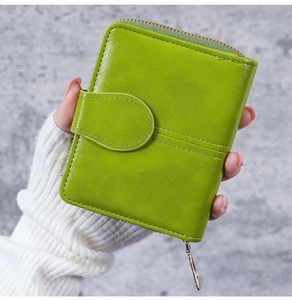 Green oil wax leather short wallet held by hand showing texture and snap button detail