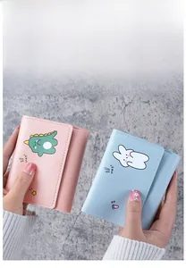 Close-up of pink and blue PU leather mini wallets featuring cute cartoon dinosaur prints