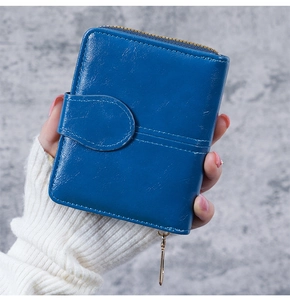 Close-up of blue oil wax leather short wallet featuring gold zipper and snap closure