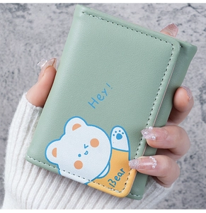 Close-up of light green trifold wallet with cute cartoon bear and smooth PU leather texture