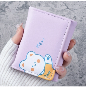Close-up of a lavender mini trifold wallet with cute bear print held by a hand