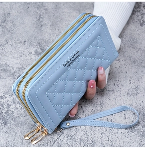 Détail du portefeuille en cuir bleu clair avec surpiqûres en losanges et zip doré