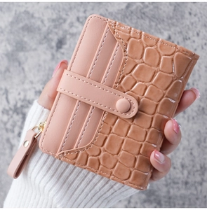 Close-up of pink faux crocodile skin wallet featuring a snap closure and zipper pocket