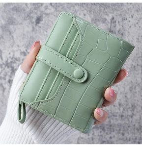 Close-up of mint green crocodile-patterned short leather wallet held in hand
