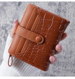 Detail of brown faux crocodile skin wallet with snap buckle and card slots