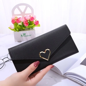 Elegant black long envelope wallet with gold heart metal buckle on marble background