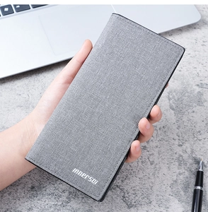 Close-up of slim long men's wallet in grey fabric texture held by hand in office setting
