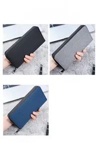 Three men's long canvas zip wallets shown in black, grey, and blue in a business setting