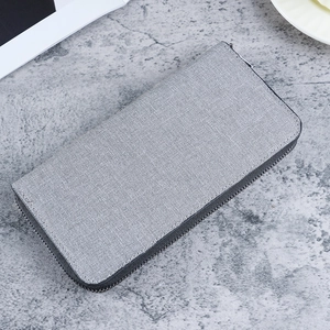 Grey canvas zip-around men's wallet with large capacity on a modern textured background