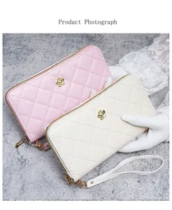 Détail de portefeuilles longs en cuir matelassé rose et beige avec breloques dorées