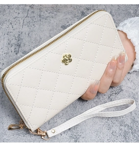Détail d'un portefeuille dragonne en cuir beige matelassé avec fleur de camélia dorée