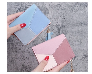 Close-up of pebble leather texture and metal chain tassel detail on bi-fold wallets