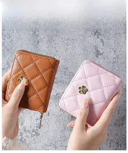 Detail view of quilted wristlet wallets in brown and pink with golden camellia ornaments