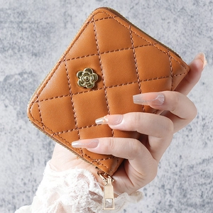Close-up of caramel quilted leather coin purse with golden camellia flower and metal zipper