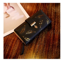 Detalle de hojas cortadas con láser y colgante de metal en cartera larga de cuero PU