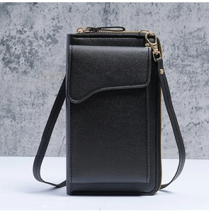 Detail of black pebbled leather crossbody phone bag with gold hardware and curved flap