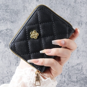 Detailed close-up of black quilted card holder with golden camellia flower accent