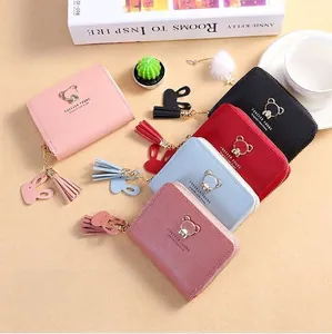 Detail of multi-color women's small wallets featuring bear logo and rabbit tassel
