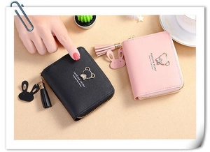 Close-up of leather mini purses with metal bear logo and tassel zipper detail