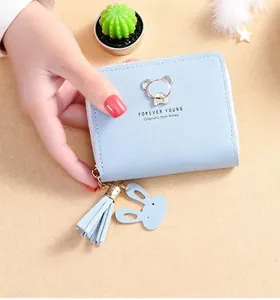 Detail of light blue faux leather wallet featuring a metal bear and tassel charm