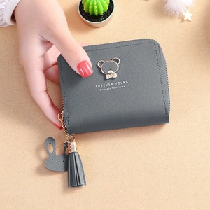 Close-up of gray tassel wallet featuring golden bear logo and rabbit pendant detail