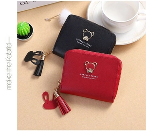 Close-up of cute bear logo and tassel charms on litchi texture women's wallets
