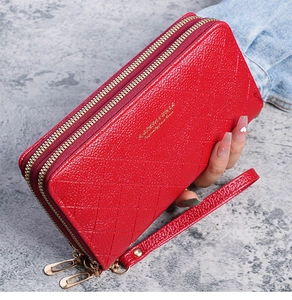 Detail of red quilted faux leather long wallet with double zippers and wrist strap
