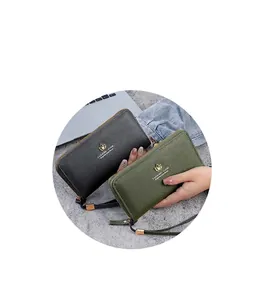 Détail de portefeuilles en cuir grainé gris et vert avec logo feuille dorée et dragonne