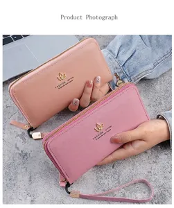 Détail d'un grand portefeuille en cuir zippé avec breloque feuille dorée et dragonne assortie