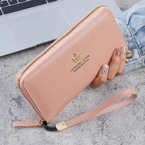 Détail du portefeuille long en cuir rose avec double fermeture éclair et ornement doré