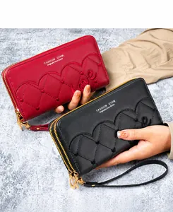 Macro-detail van wijnrode en zwarte langwerpige clutches van PU-leer met hartstiksels