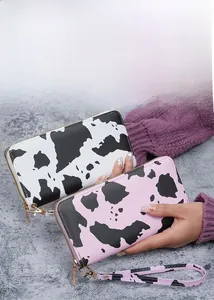 Detail of cow print long zip wallets with gold hardware and wristlet straps