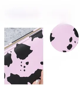 Detail of cow print faux leather wallet featuring a premium gold zipper and pink texture
