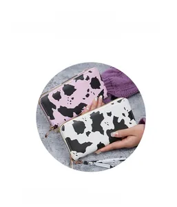 Detail of long zippered cow print wallets featuring cowhide pattern and wrist straps