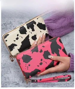 Detailed view of long zipper wallets in cow print with matching wrist straps