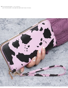 Detail of pink cow print long wallet featuring gold zipper and matching wrist strap