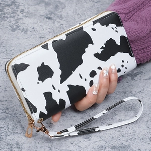 Detail of a large capacity long clutch wallet with black and white cow print and gold zipper