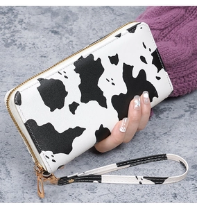 Detail of a cow pattern long wallet with gold zipper and detachable wrist strap