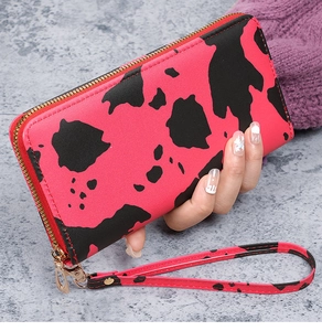 Detail of pink cow print clutch wallet with gold zipper and detachable wristlet strap