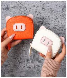 Close-up of cute pig-shaped coin purses in orange and white litchi pattern leather