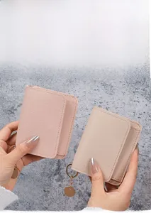Close-up of minimalist pebble leather card holders in pink and khaki with gold pendants