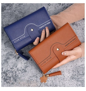Detail of long tri-fold wallet with lychee grain leather, tassels and floral charm
