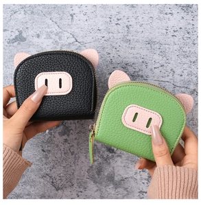 Detailed view of pig-shaped coin purses in black and green lychee grain leather