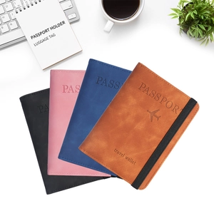Flat lay of multiple PU leather passport covers in black, pink, blue, and brown on a desk