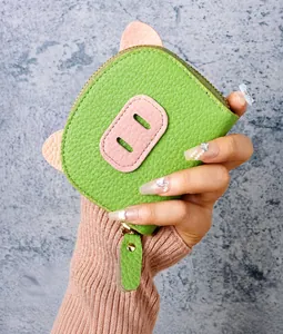 Handheld view of a green pig-shaped card holder with lychee pattern and pink ears detail