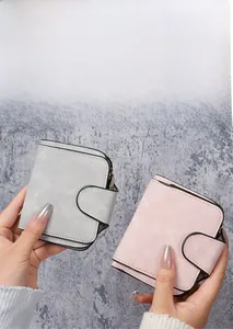 Detail showing grey and pink short wallets in matte faux leather with secure snap closure